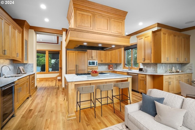 kitchen featuring ornamental molding, sink, light hardwood / wood-style flooring, and beverage cooler