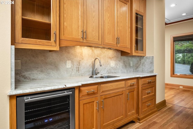 kitchen with glass insert cabinets, tasteful backsplash, wood finished floors, a sink, and wine cooler