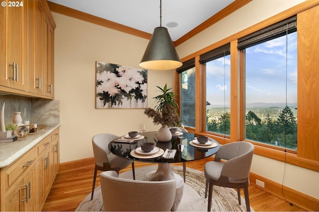 dining area with crown molding, light hardwood / wood-style floors, and a healthy amount of sunlight