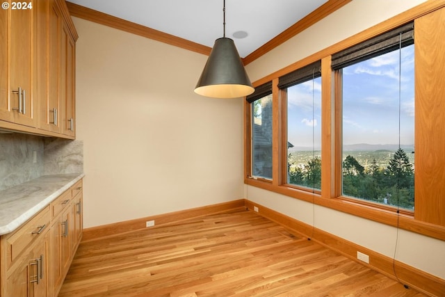 unfurnished dining area with light wood-type flooring, a healthy amount of sunlight, and crown molding