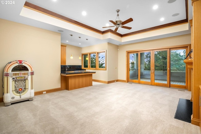 unfurnished living room with ornamental molding, light carpet, and a tray ceiling