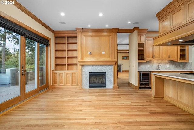 kitchen featuring decorative backsplash, light hardwood / wood-style floors, beverage cooler, ornamental molding, and sink