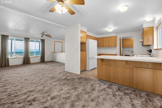 kitchen featuring white refrigerator, light colored carpet, kitchen peninsula, and sink