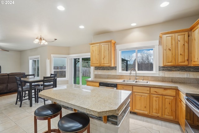 kitchen featuring appliances with stainless steel finishes, sink, a breakfast bar area, a chandelier, and light tile patterned floors