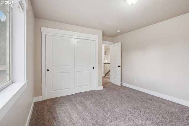 unfurnished bedroom with multiple windows, a closet, and carpet