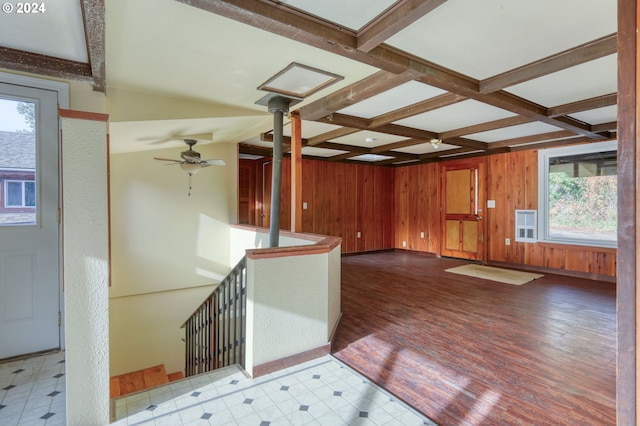 unfurnished living room with coffered ceiling, ceiling fan, wooden walls, beam ceiling, and hardwood / wood-style flooring