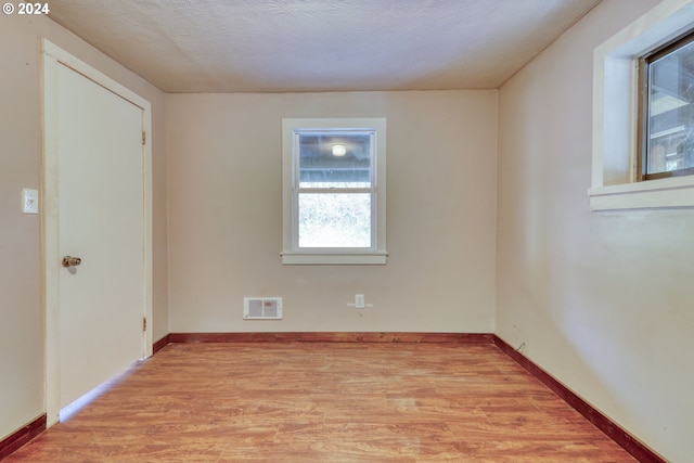 spare room with light wood-type flooring and a textured ceiling