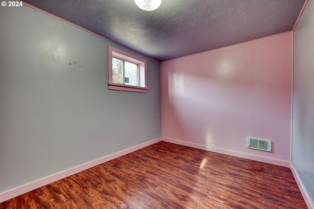 empty room with a textured ceiling and hardwood / wood-style flooring