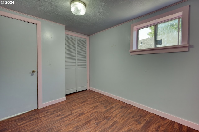 unfurnished bedroom with a textured ceiling, crown molding, and dark wood-type flooring