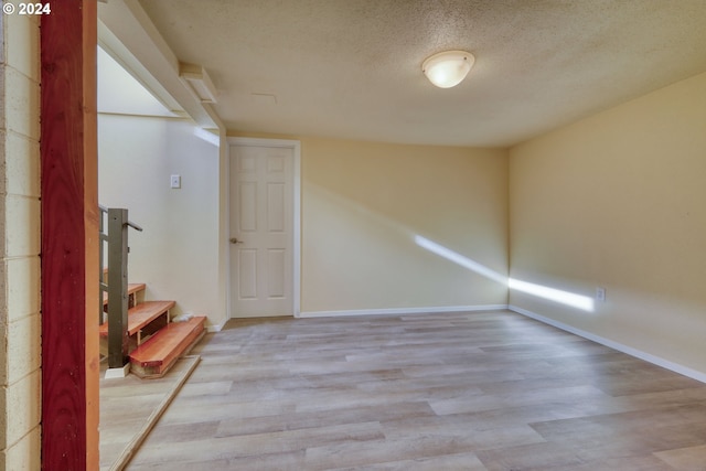 unfurnished room with a textured ceiling and light hardwood / wood-style flooring