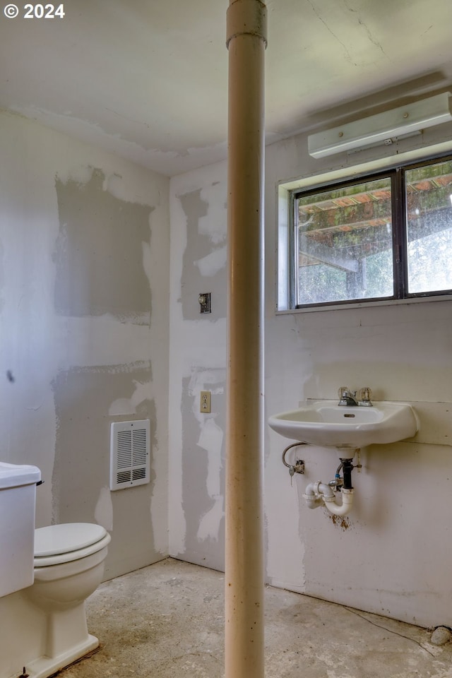 bathroom with toilet and concrete flooring