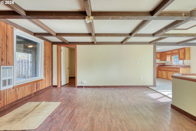 unfurnished living room featuring wooden walls, light hardwood / wood-style flooring, beamed ceiling, and coffered ceiling