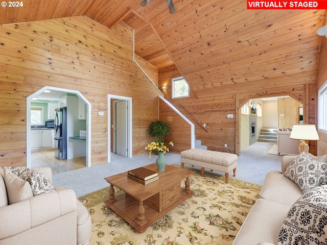 living area with stairway, arched walkways, wood walls, and light carpet