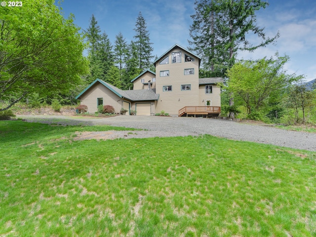 view of front facade with a garage, a wooden deck, and a front lawn