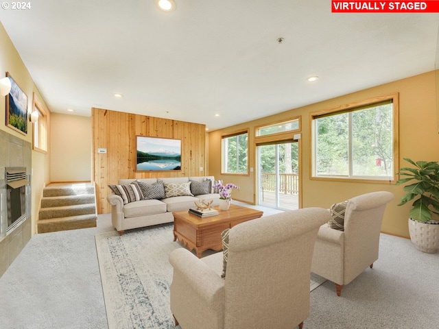 carpeted living room with wooden walls and a tile fireplace