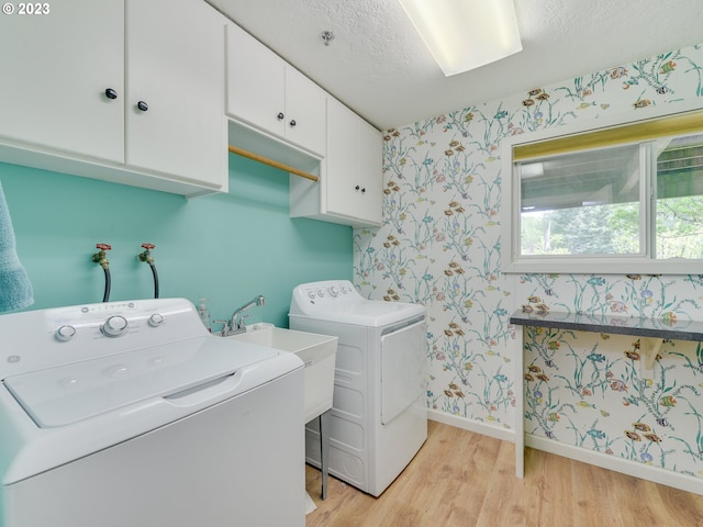 laundry area featuring wallpapered walls, light wood-type flooring, cabinet space, a textured ceiling, and independent washer and dryer