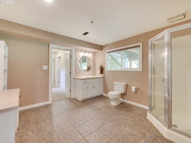 bathroom featuring vanity, a shower with shower door, and toilet