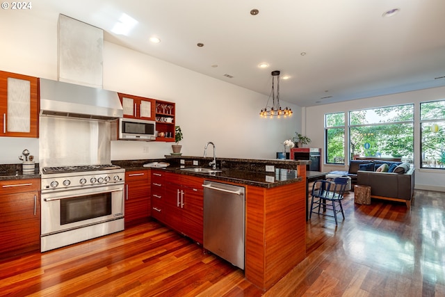 kitchen with sink, dark wood-type flooring, stainless steel appliances, decorative light fixtures, and dark stone counters