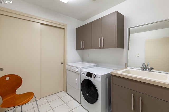 clothes washing area with light tile patterned flooring, cabinets, sink, and washing machine and clothes dryer