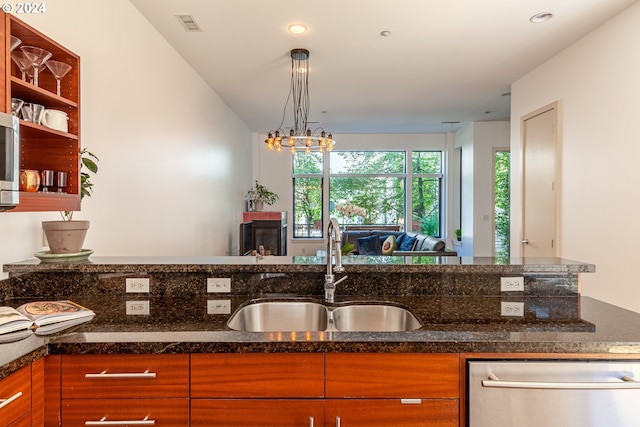 kitchen featuring dishwasher, sink, hanging light fixtures, and dark stone countertops