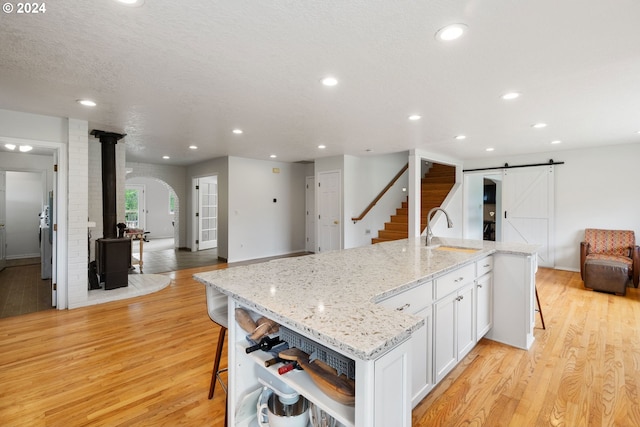 kitchen with a large island, sink, light hardwood / wood-style flooring, a breakfast bar, and white cabinets