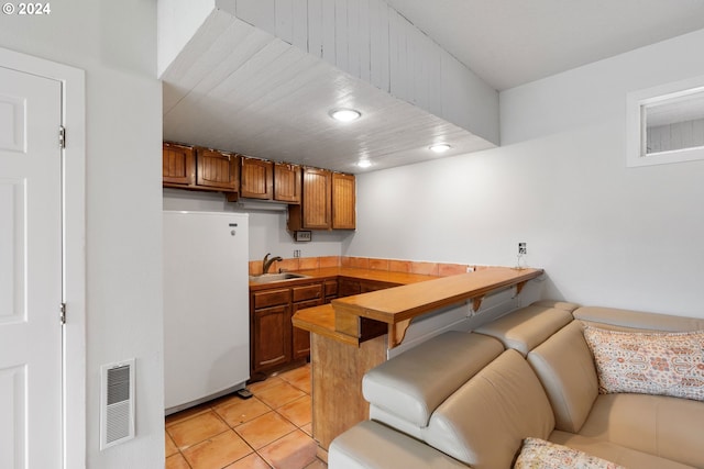 kitchen with white refrigerator, light tile patterned flooring, and sink