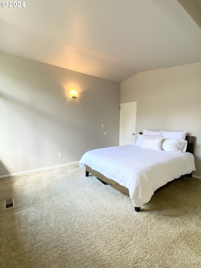 carpeted bedroom with baseboards, visible vents, and vaulted ceiling