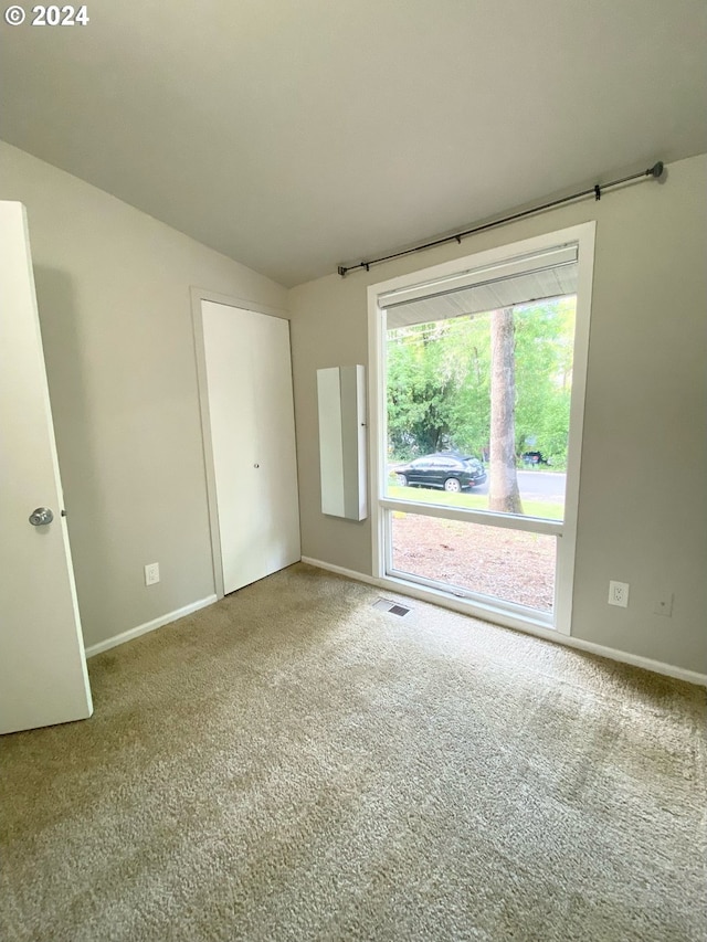 carpeted spare room with lofted ceiling, visible vents, and baseboards