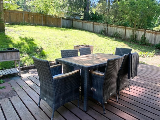 wooden deck with outdoor dining space, a lawn, and a fenced backyard