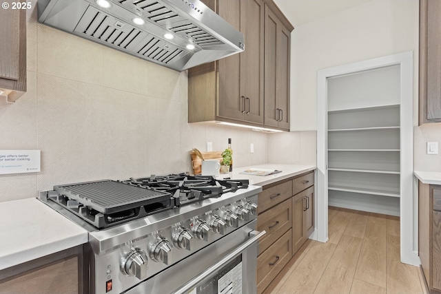 kitchen featuring light countertops, custom range hood, light wood-style flooring, and high end stove