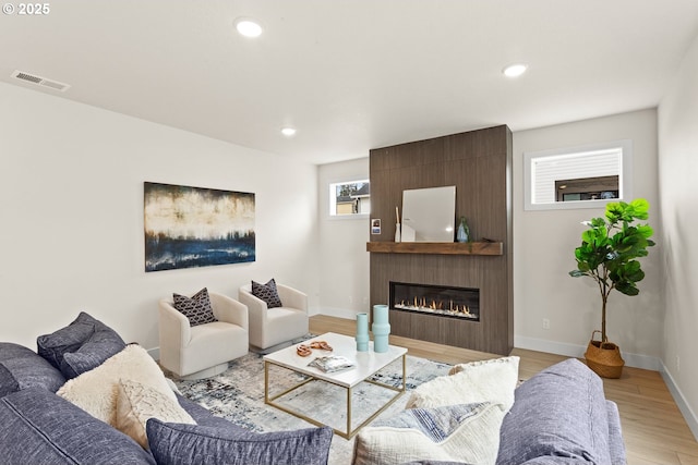 living area with visible vents, baseboards, light wood-style floors, a fireplace, and recessed lighting