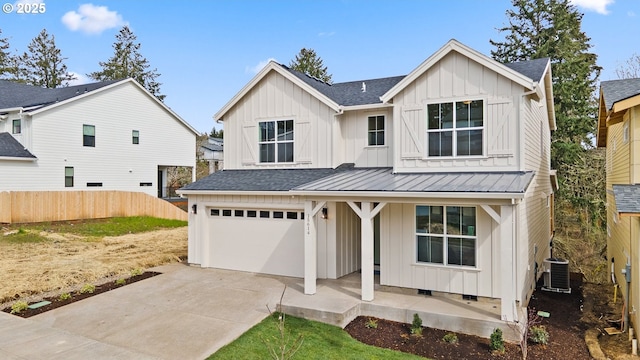modern farmhouse with concrete driveway, board and batten siding, an attached garage, central AC unit, and fence