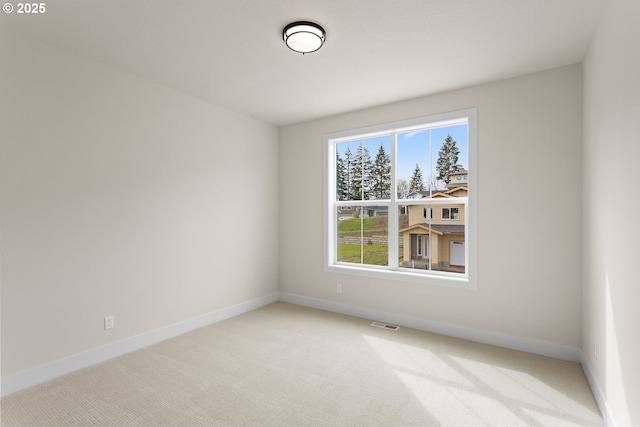 empty room featuring light carpet, baseboards, and visible vents