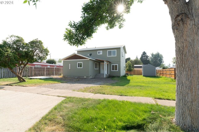 view of front of property featuring a front lawn, a storage shed, and a patio