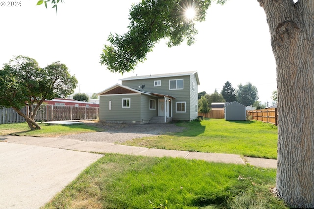 view of front of home featuring a fenced backyard, a front yard, an outdoor structure, and a shed