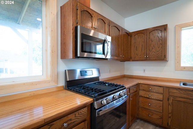 kitchen with stainless steel appliances, brown cabinets, and light countertops