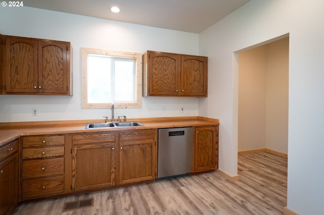 kitchen featuring dishwasher, brown cabinets, light countertops, light wood-style floors, and a sink