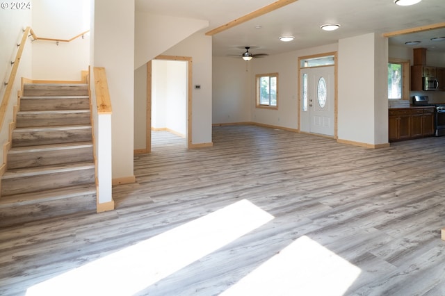 entryway featuring stairs, ceiling fan, light wood-type flooring, and baseboards