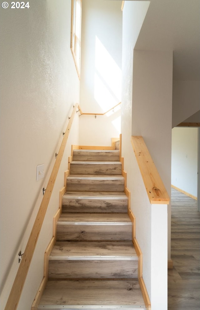 staircase featuring baseboards and wood finished floors