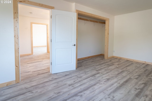 unfurnished bedroom featuring light wood finished floors, a closet, and baseboards