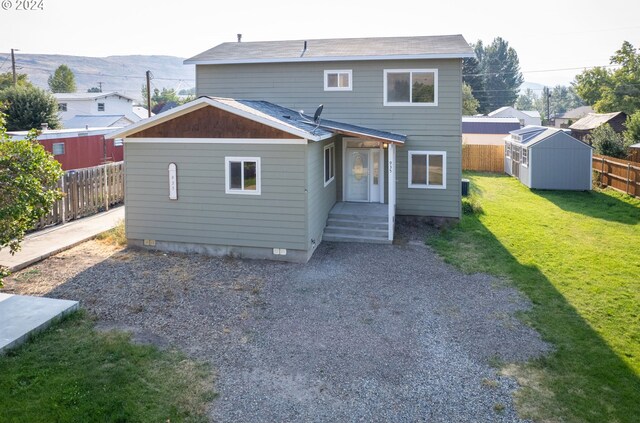 rear view of house with a lawn and a storage unit