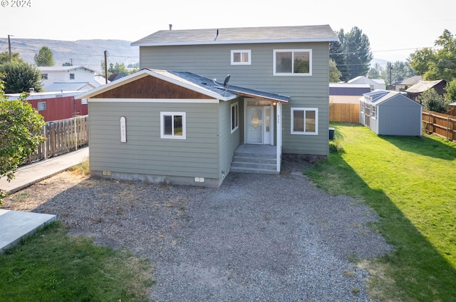 back of house with a yard, a storage unit, fence, driveway, and an outdoor structure