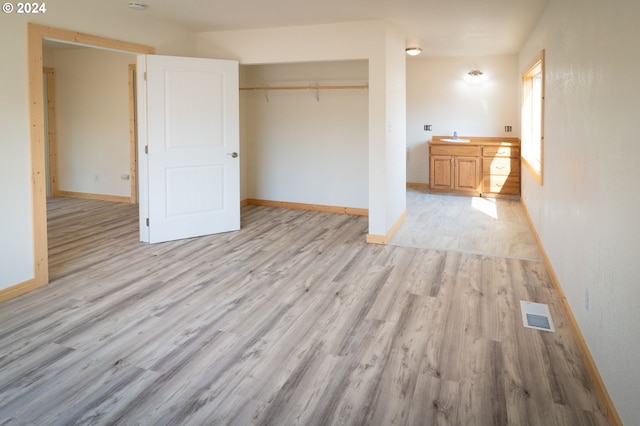 unfurnished bedroom featuring light wood-style flooring, a closet, visible vents, and baseboards