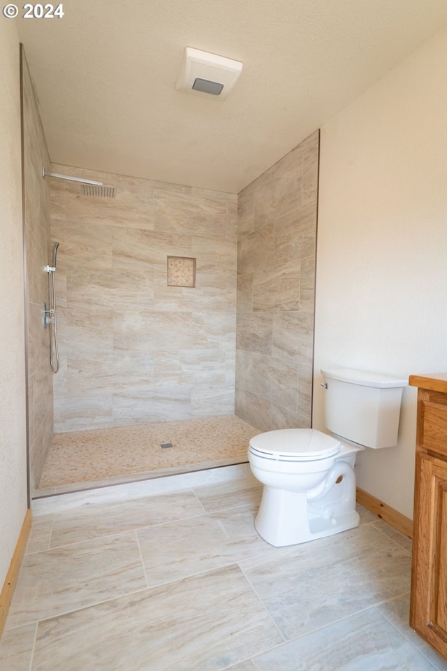 bathroom featuring toilet, a stall shower, baseboards, and vanity