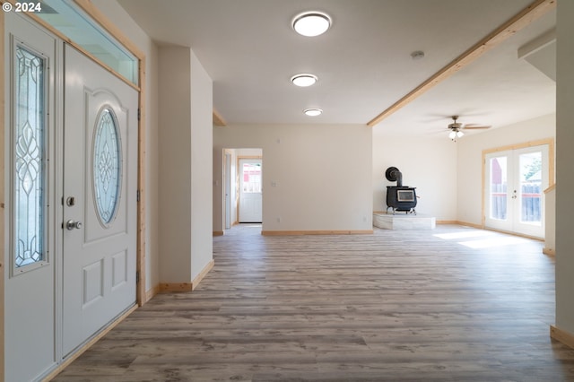 foyer entrance with a wood stove, baseboards, french doors, and wood finished floors