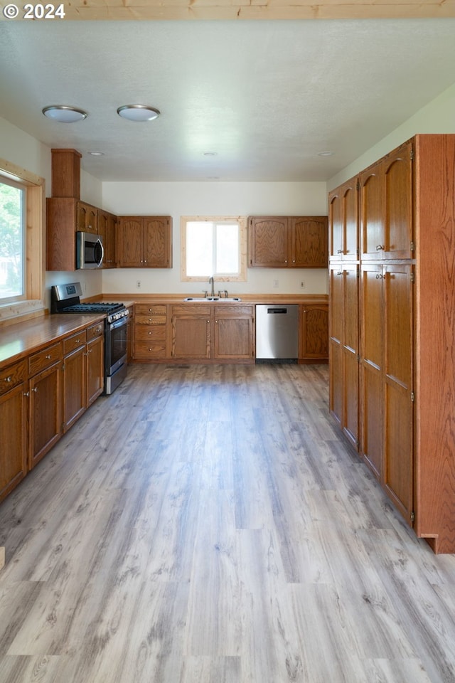 kitchen featuring plenty of natural light, appliances with stainless steel finishes, light wood-type flooring, and brown cabinets