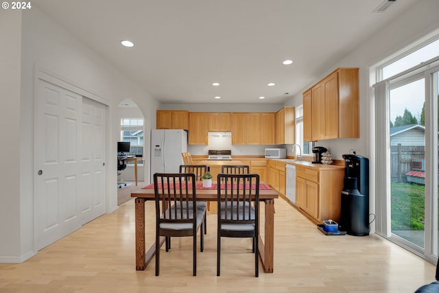 kitchen featuring plenty of natural light, white appliances, sink, and light hardwood / wood-style flooring