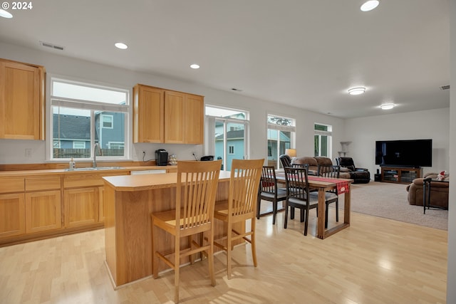 kitchen featuring a breakfast bar, light brown cabinetry, light hardwood / wood-style floors, and sink