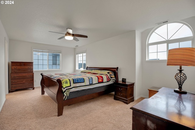 carpeted bedroom featuring ceiling fan, a textured ceiling, and multiple windows