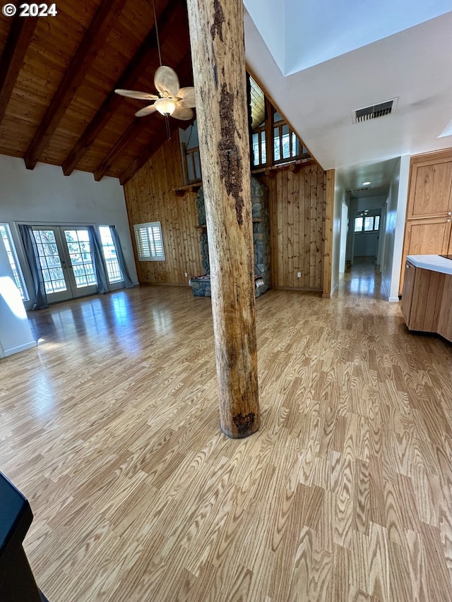 unfurnished living room with beam ceiling, high vaulted ceiling, wooden walls, and wood ceiling